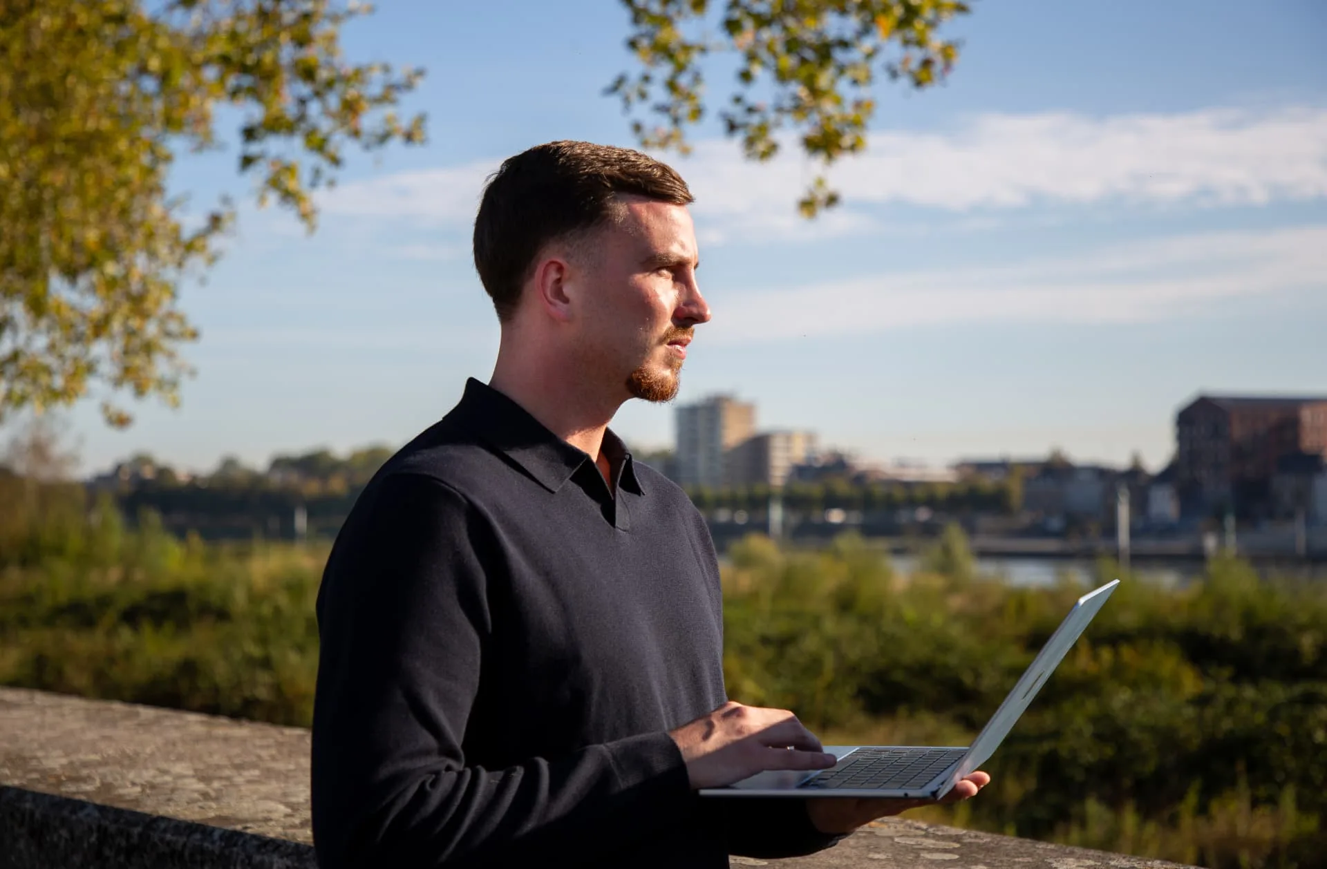 Gielke Huijs kijkt met zijn laptop uit over de Maas in Venlo